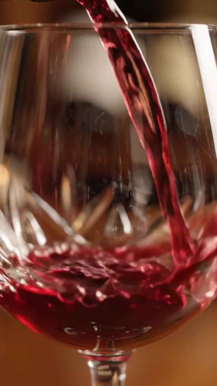 Momenti Accattivanti di Vino Versato in un Bicchiere di Cristallo, che Mostra Colore Ricco ed Eleganza in Ogni Goccia