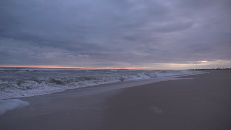stormy weather at the beach with rough sea and overcast dramatic sky during sunset slow motion - wide static shot