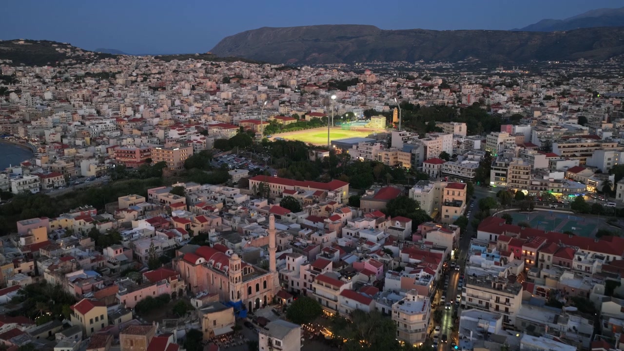 Vista aérea de drone em alta altitude da cidade velha com seu minarete otomano e a cidade iluminada, Chania, Grécia