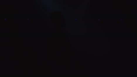 silueta retroiluminada de saxofonista hombre con saxofón en un estudio de club nocturno oscuro y empezar a tocar el saxofón