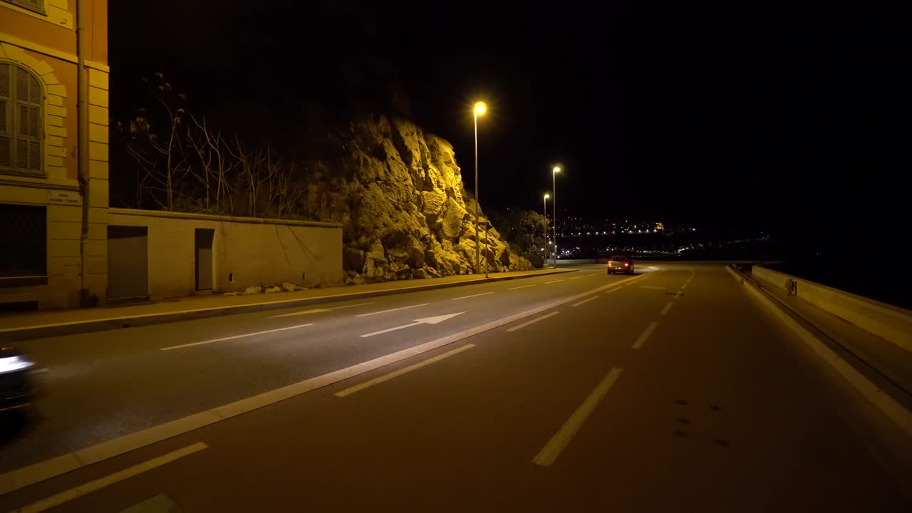 Auto che sfrecciano nella città notturna buia.