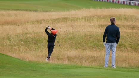 child practicing golf swing with adult supervision