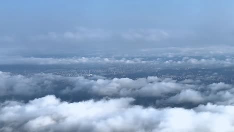 A-sprawling-cityscape-obscured-by-a-dramatic-layer-of-clouds,-hinting-at-urban-mystery,-aerial-view