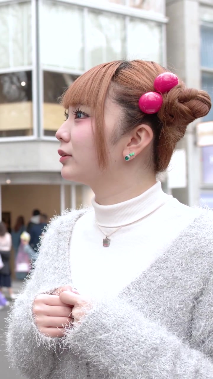 Halvtotalbilde av en stilig kvinne i en lodden cardigan som står utendørs i Tokyo, Japan.