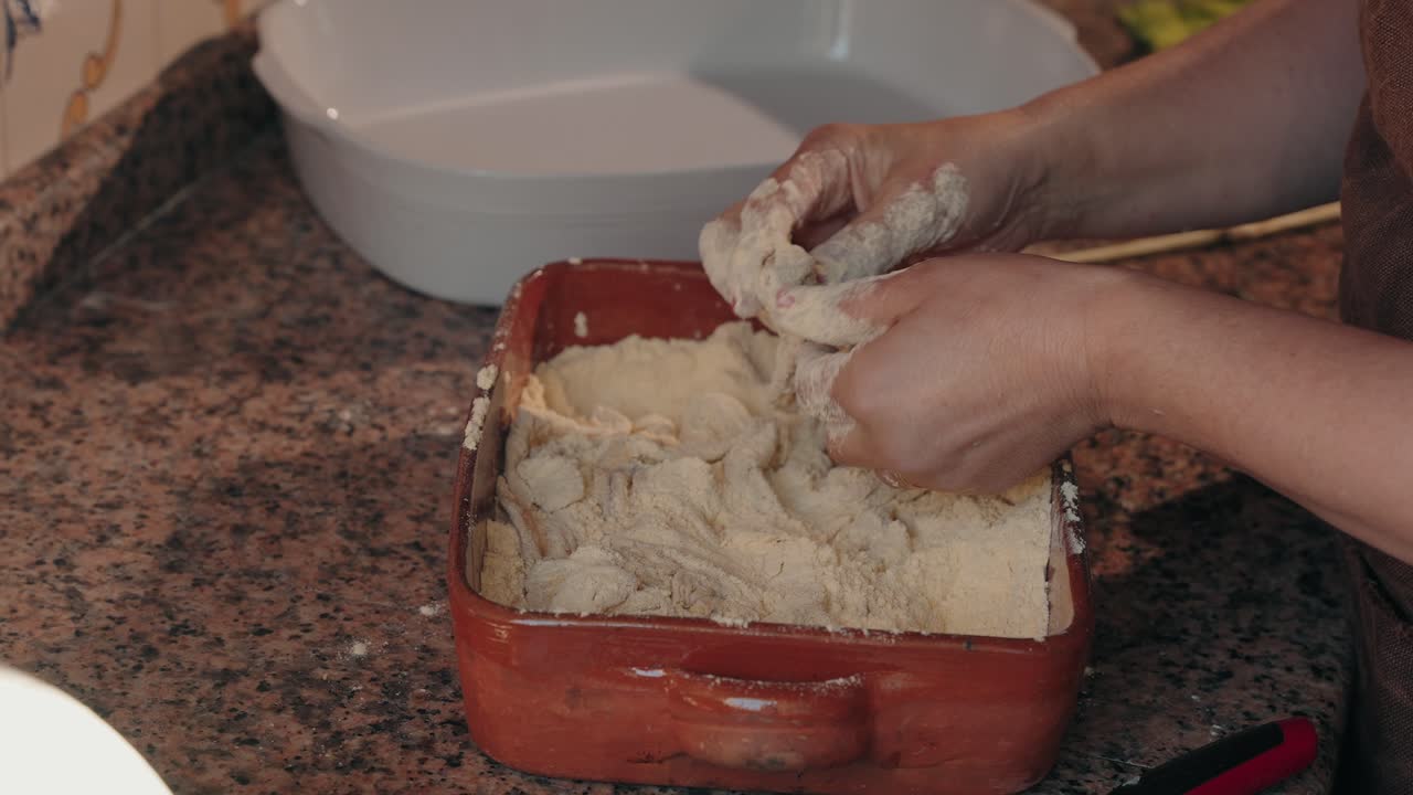 Hands scrubbing pork intestines with flour in ceramic dish in Portugal