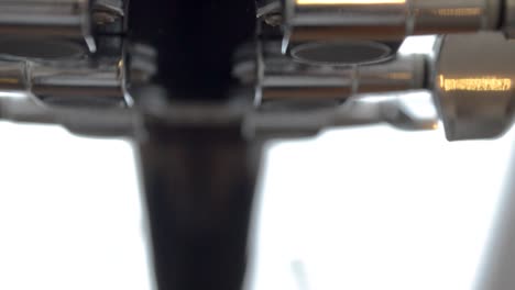 silver colored guitar tuning mechanism on a black acoustic guitar neck, close up