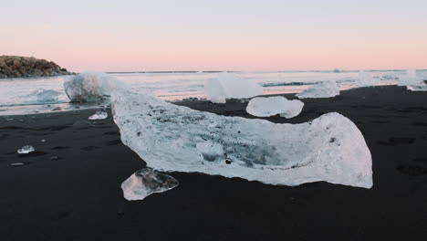 Pequeños-Trozos-De-Hielo-Sentados-En-La-Arena-Negra-De-Diamond-Beach,-Islandia