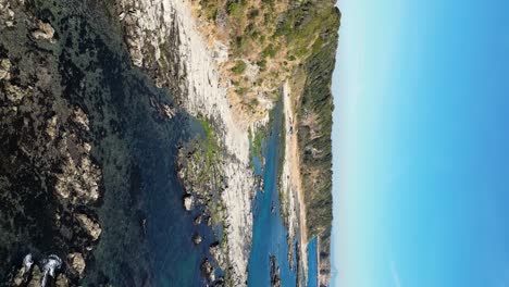 Vertical-drone-flight-over-beautiful-rugged-stone-coastline-on-clear-day