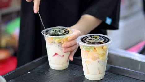 hands preparing mixed fruit desserts in hanoi