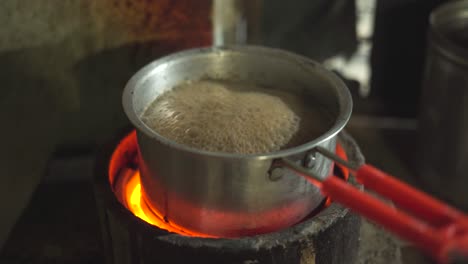 making milk tea or indian chai in a pan inside kitchen of an indian dhaba or restaurant