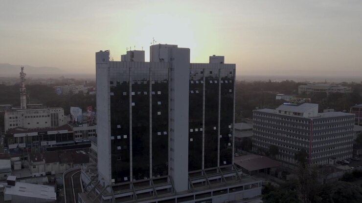Tomada aérea do nascer do sol passando ao lado de um edifício em Kisumu com a hora dourada