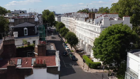 Forwards-fly-over-row-of-houses.--Big-white-town-houses-lit-by-bright-sun.-Elevated-view-of-street-in-residential-borough.-London,-UK