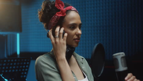 retrato de la encantadora joven cantante feliz mirando y sonriendo alegremente a la cámara en el micrófono en el estudio de grabación de sonido
