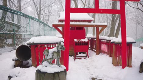 snow falls over kitsune shrine at fox village, miyagi japan