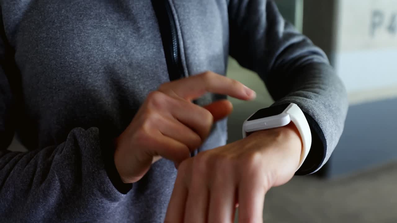Donna che usa uno smartwatch in un parcheggio sotterraneo 4K.