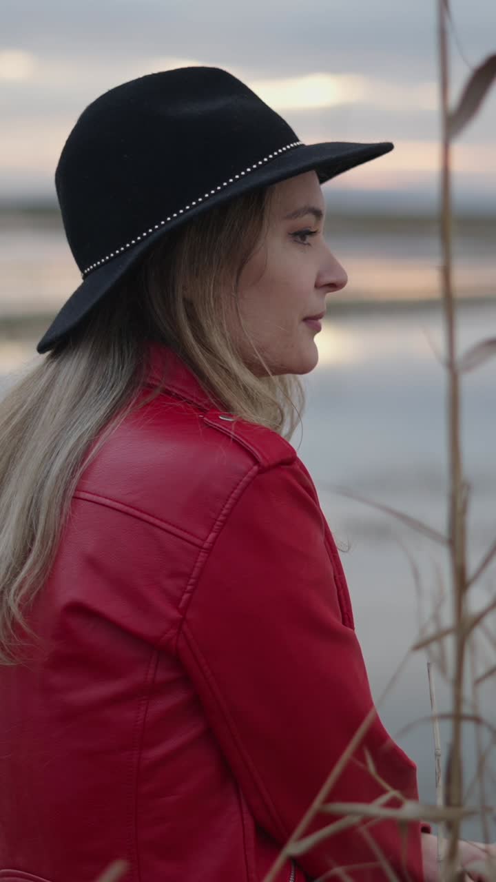 Donna con giacca e cappello rossi vicino a un lago