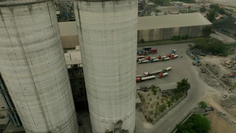 drone perspective of massive cement silos within an industrial factory setting.