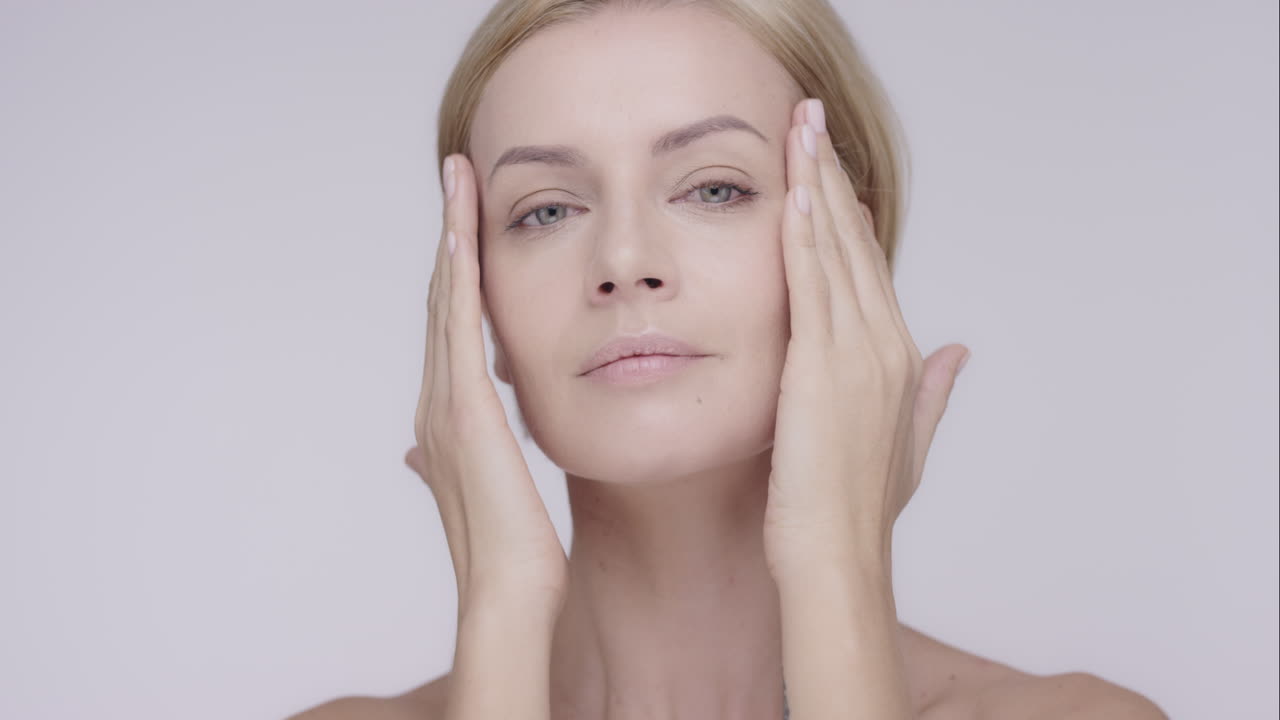 bela mulher saudável tocando pele lisa no rosto em câmera lenta para beleza conceito de cuidados com a pele em um fundo cinza dragão épico vermelho
