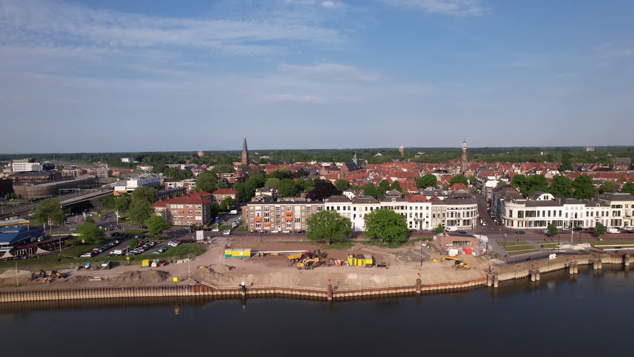 Construction site of medieval city seen from above with inland shipping large cargo vessel leaving ripple waves on river IJssel passing IJsselkade boulevard cityscape of tower town Zutphen