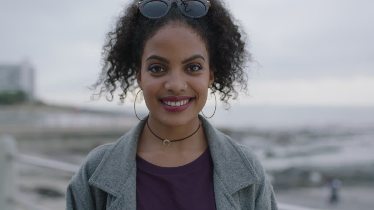 retrato de una atractiva mujer hispana de pie en la playa sonriendo alegremente