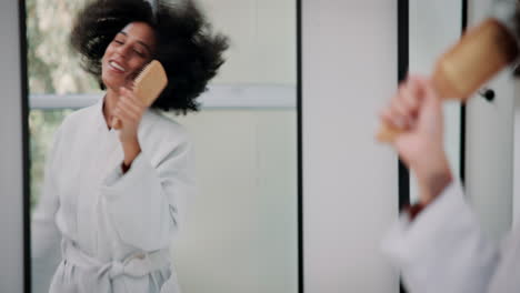 woman brushing her curly hair in the bathroom mirror