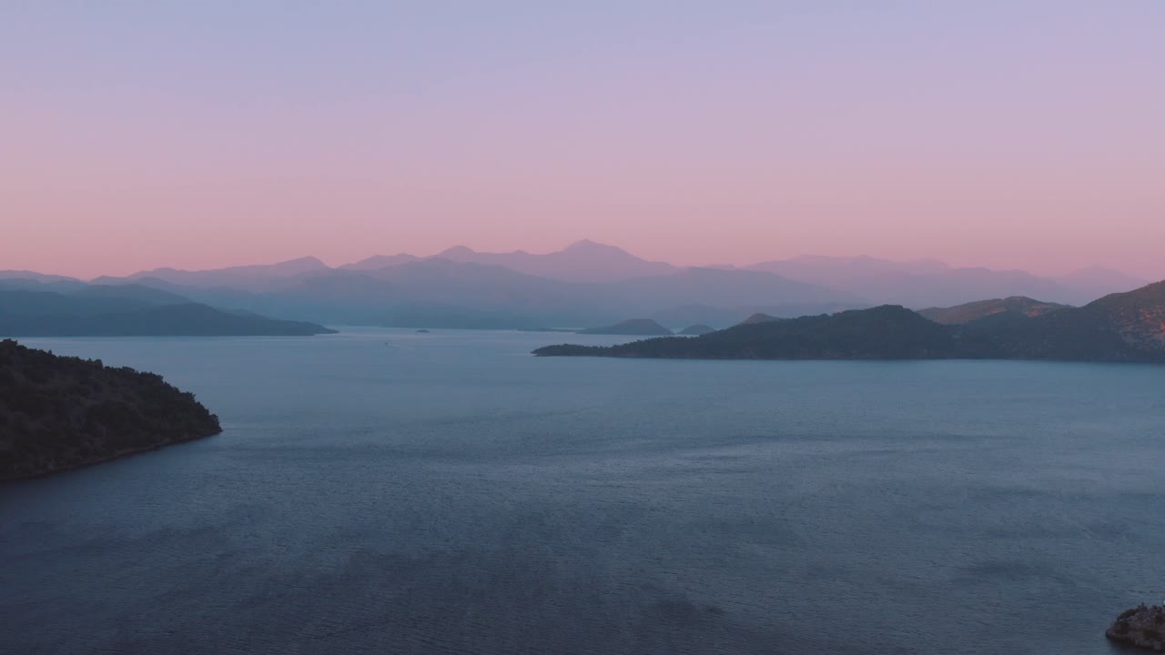 지중해 상공을 날고 있는 무인 항공기는 마르마리스와 로도스, 터키 - 그리스 근처의 맑고 푸른 물과 함께 석양의 보라색 하늘에 범선과 요트 보트로 가득 차 있습니다.