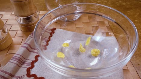 crispy yellow corn flakes into the bowl for the morning a delicious breakfast with milk. slow motion with rotation tracking shot.