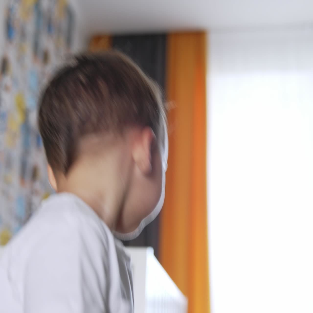 Beautiful Caucasian boy stands looking focused down. Child turns around and leaves. Low angle view