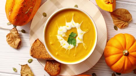 creamy pumpkin soup in bowl with herb