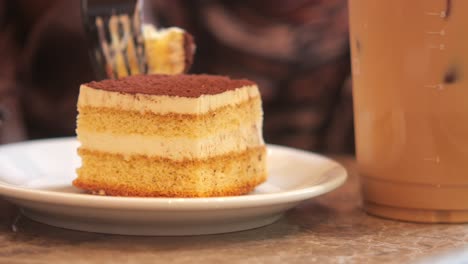 a slice of tiramisu cake and a glass of iced coffee