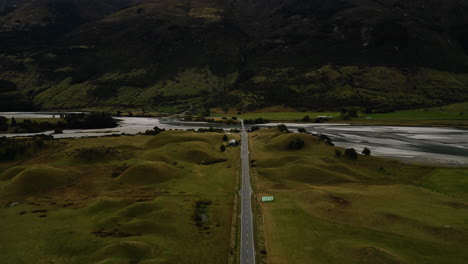 beautiful road bridge over river near mountain ranges in new zealand, aerial view