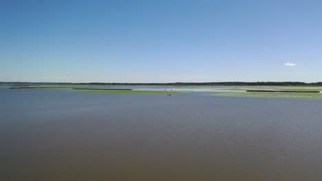 Lonely-Boat-on-Sea-Far-Away-Near-Shoreline,-Aerial-Long