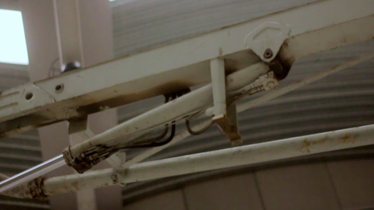 Close-up of a hydraulic joint and metal support structure inside an industrial facility, highlighting the mechanical detail and worn textures of heavy-duty equipment