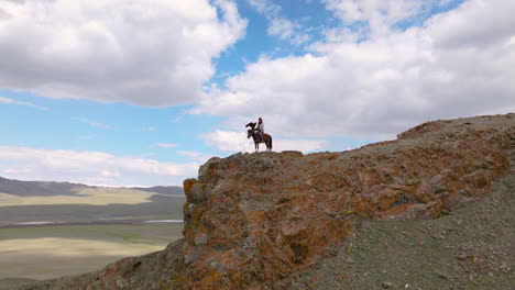 cazador de águila en la cima del acantilado en el oeste de mongolia - retirada aérea