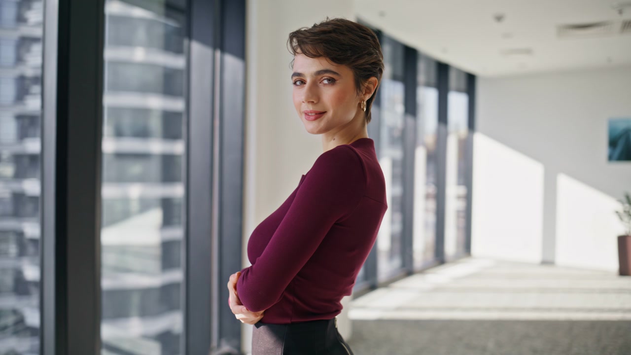 Empresária virando-se para a câmera sorrindo no escritório. Retrato de senhora bem-sucedida.