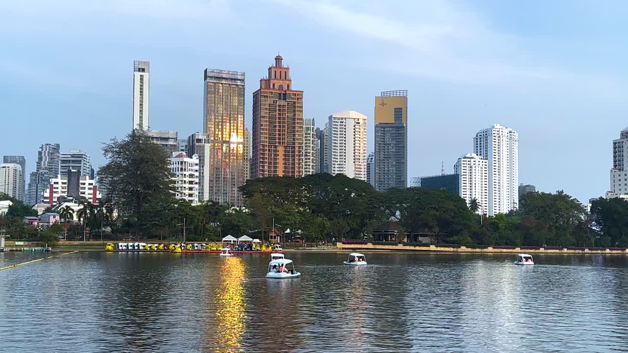 도시 스카이라인과 함께 연못에서 보트가 미끄러집니다.