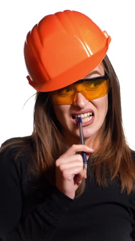 pretty woman engineer in an orange helmet tells a story about something and holds a folder-tablet with pen in her hands on a white background. vertical video