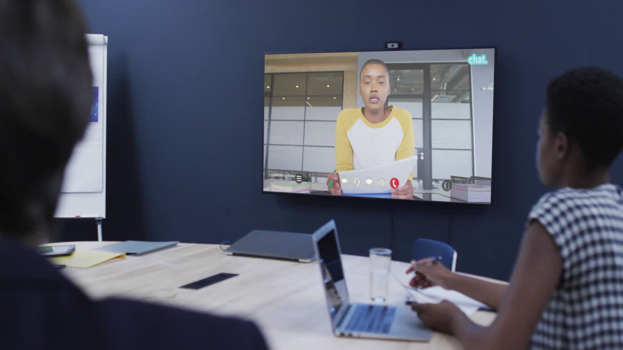 Diverse business people on video call with african american male colleaguge on tv screen