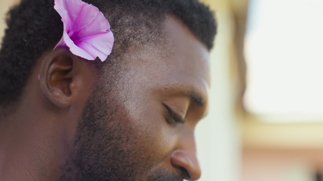 Un gentleman serein tenant une fleur sous le soleil. Un poète de rue discret profitant d'un moment paisible en extérieur sous une lumière dorée. Un gentleman portant une fleur au milieu d'un cadre extérieur tranquille sous un soleil chaleureux.