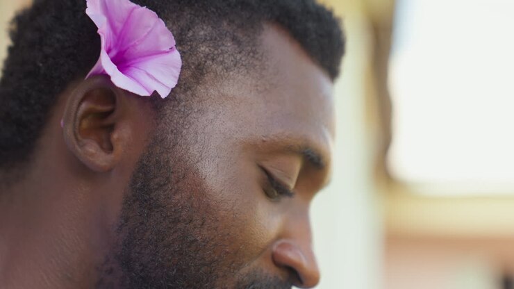 Serene gentleman holding blossom in sunlight. Quiet street poet enjoying peaceful moment outdoors with golden light. Gentleman carrying flower amidst tranquil outdoor setting under warm sunlight