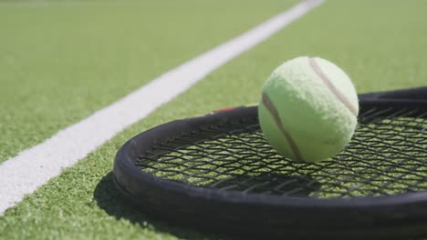 Close-up-of-tennis-racket-and-ball-on-tennis-court-on-sunny-day