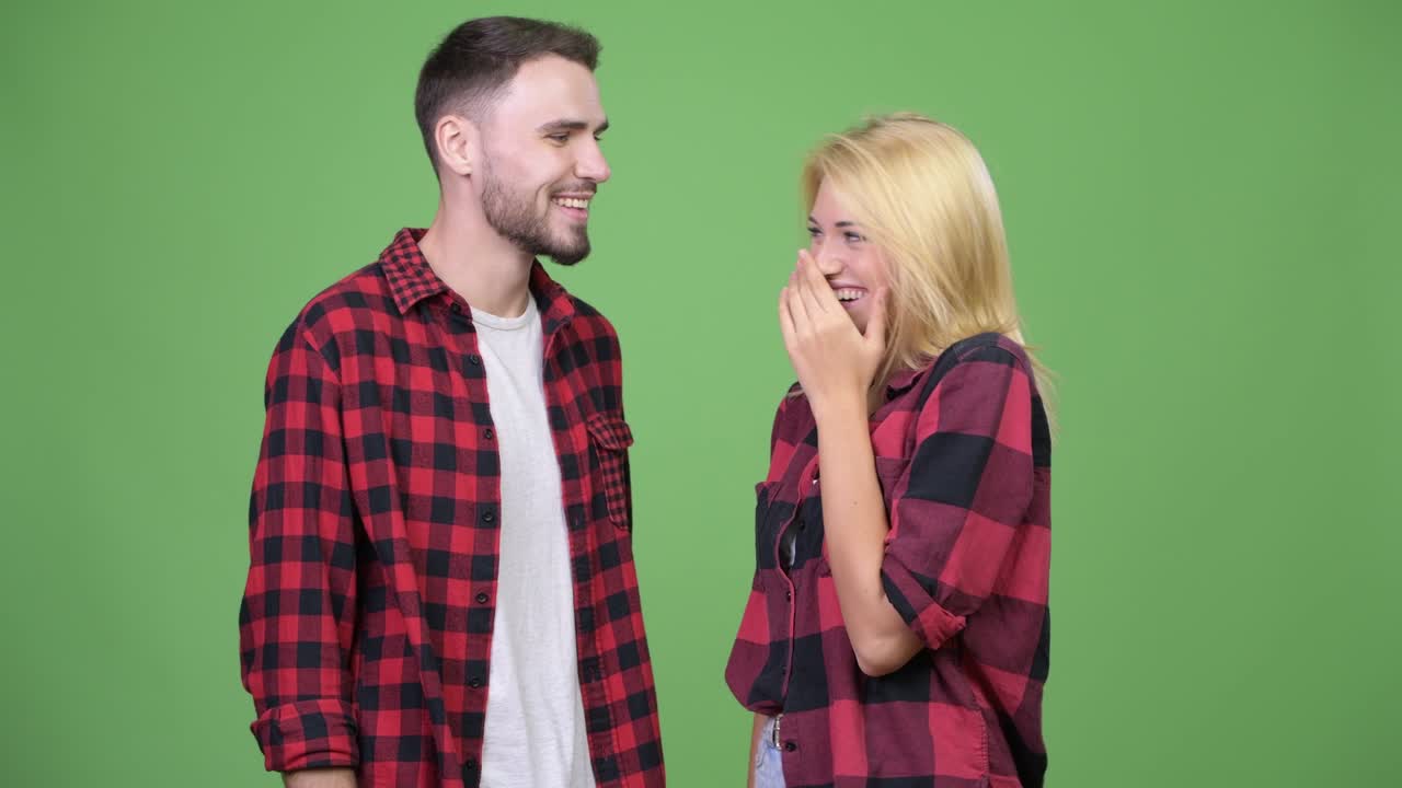 Young man whispering to young woman and laughing