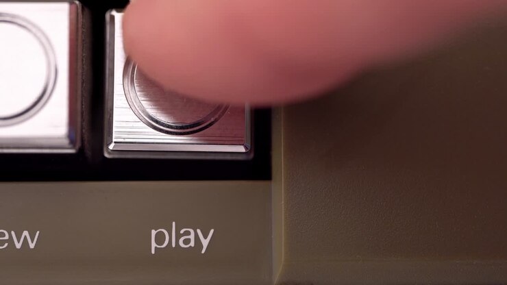 Play button of a vintage tape recorder pressed by a finger macro