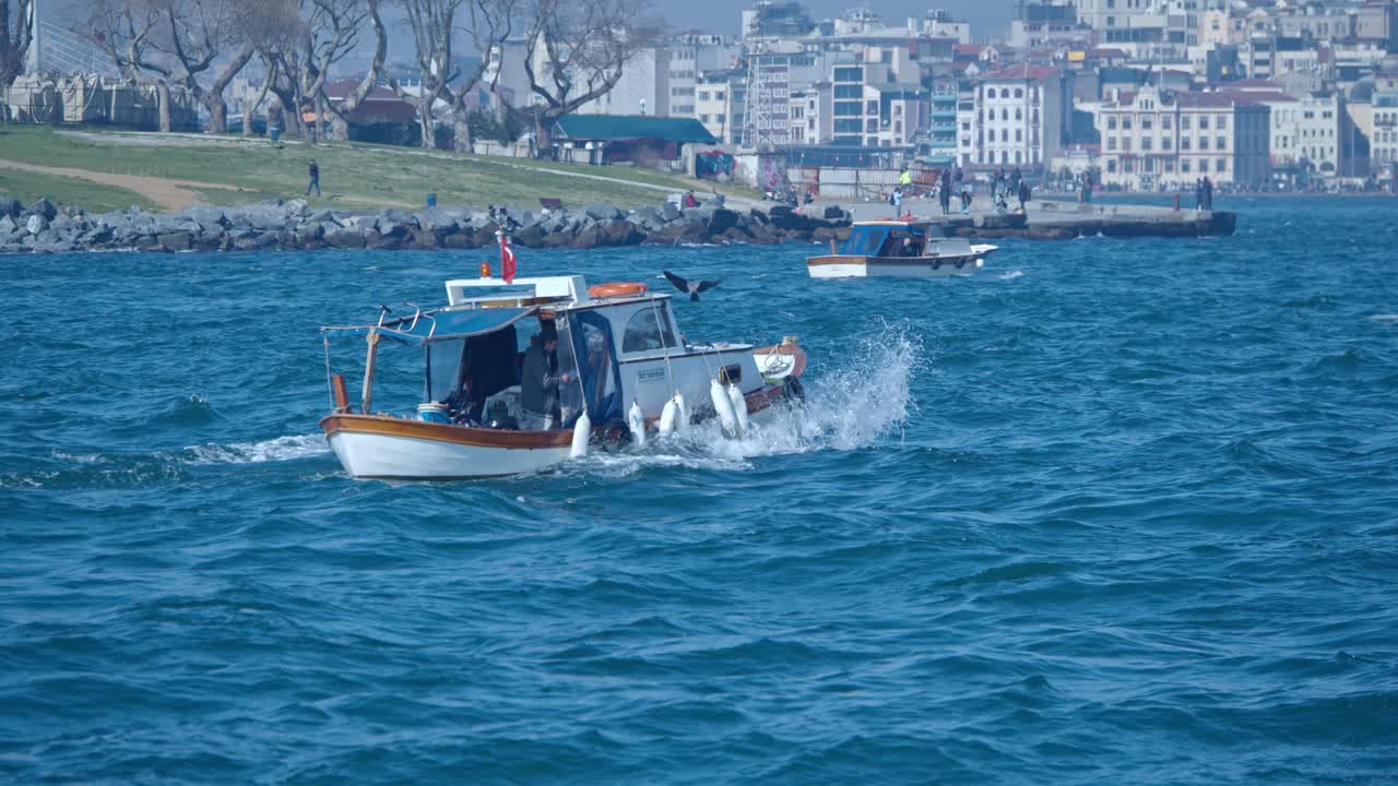 2마리의 까마귀가 앞에 앉아 있는 작은 어선, 이스탄불에서 좁은 보스포러스의 파도와 함께 춤을 춥니다.