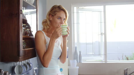 una rubia linda tomando café en la cocina.