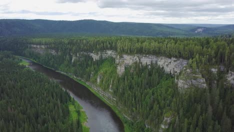 aerial view of a river winding through a forest valley with steep cliffs