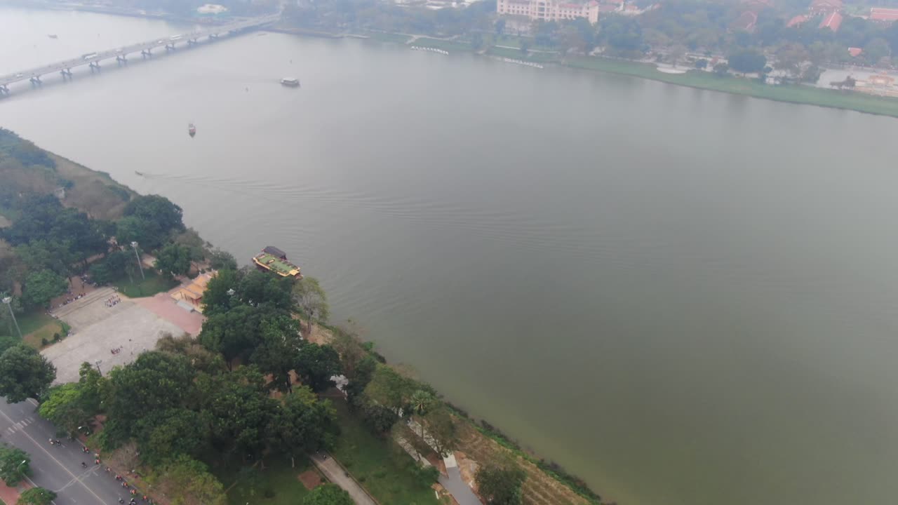 vista aérea de drones en vietnam volando sobre la ciudad imperial de hue con un amplio río, carreteras, conducción de tarjetas y edificios en un día nublado y brumoso