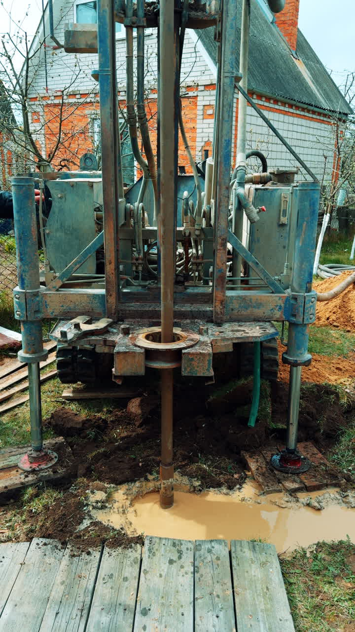 Special equipment drilling the pore in the ground. Boring machine making the water well in the household. Vertical video.
