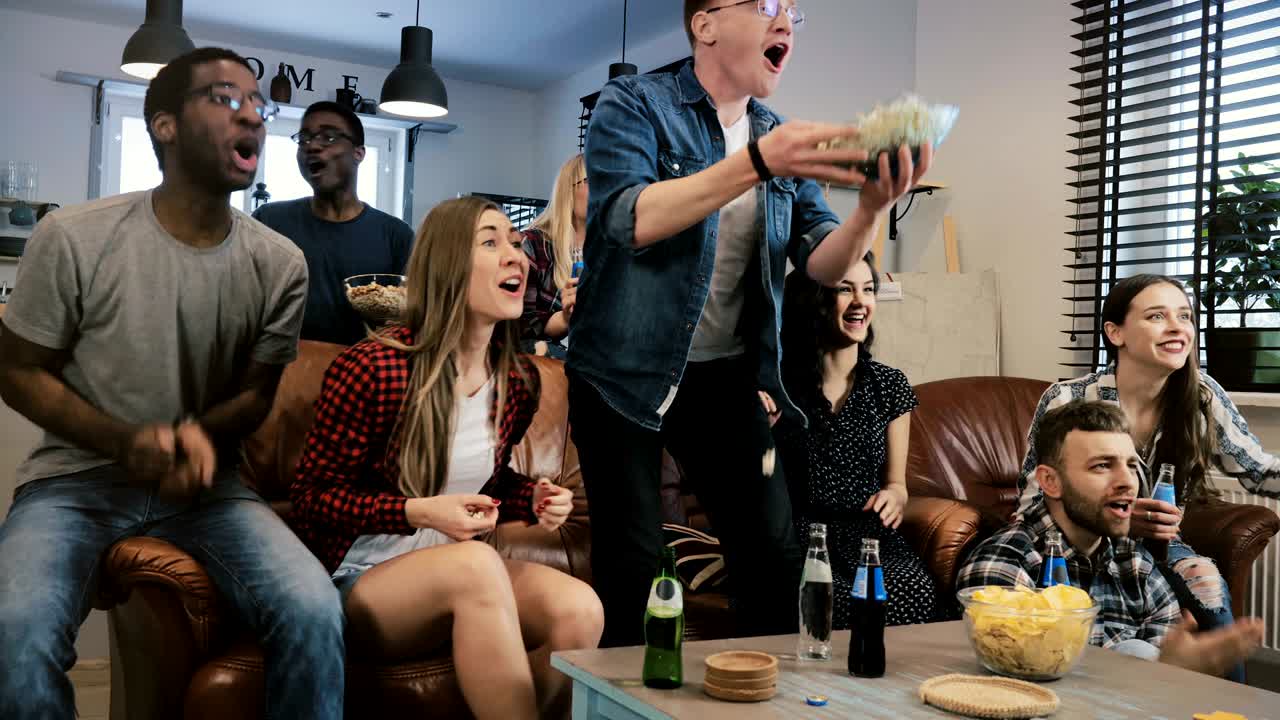 다민족, 행복한 스포츠 팬들이 골을 축하합니다. 4k 슬로 모션. 아프리카계 미국인 친구들이 tv에서 좋아하는 팀을 지지합니다.