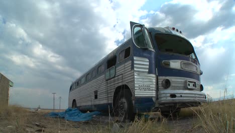 Eine-Bewegende-Zeitrafferaufnahme-Eines-Verlassenen-Greyhound-Busses-Auf-Einem-Feld